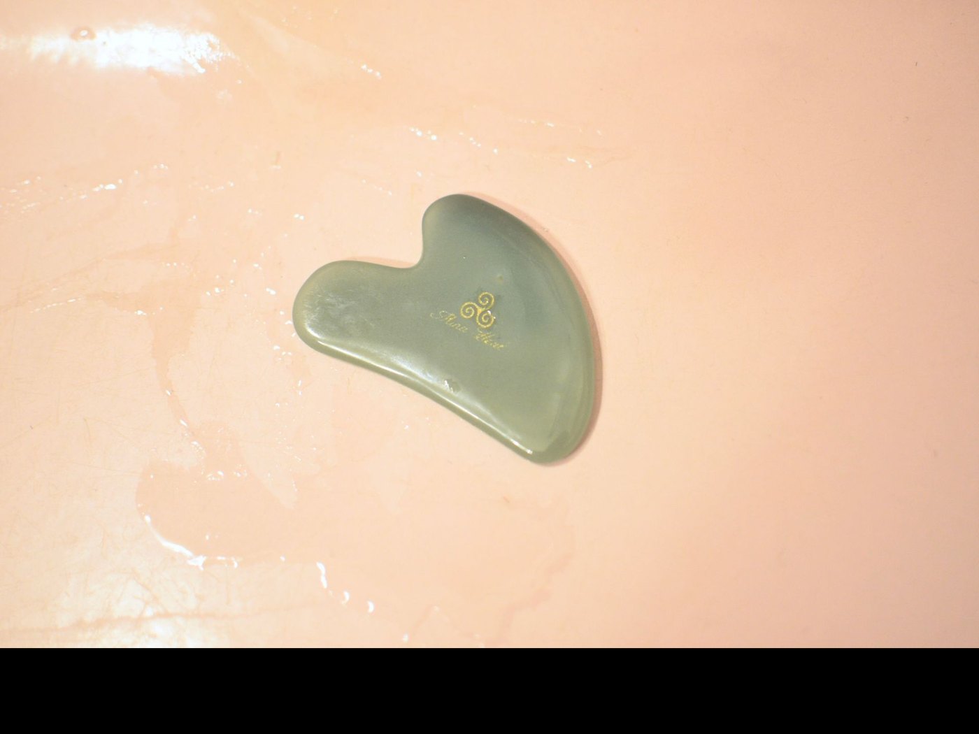 Pierre de gua sha en jade posée sur une surface claire