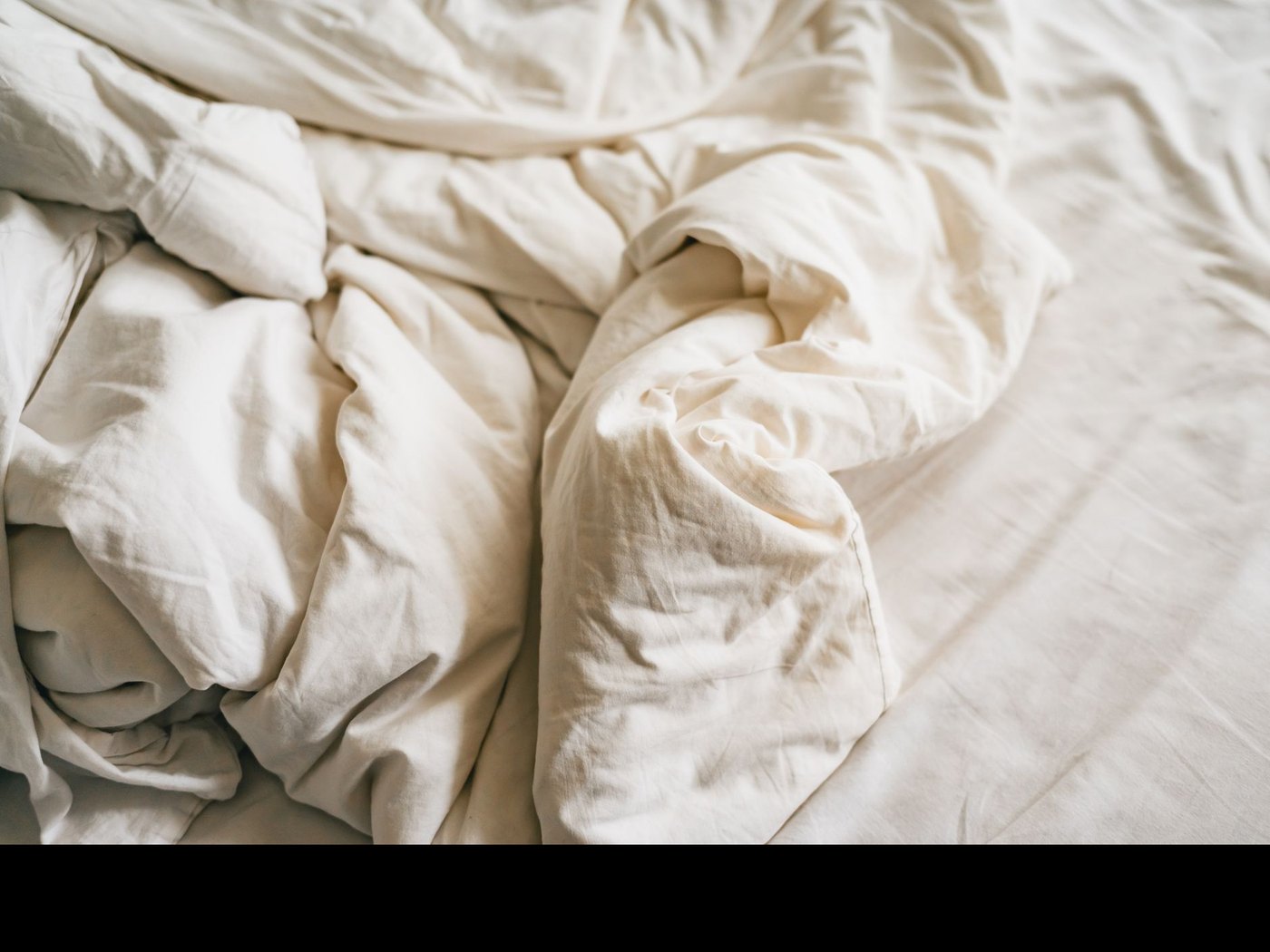 Linge de lit en lin crème, dans une lumière douce